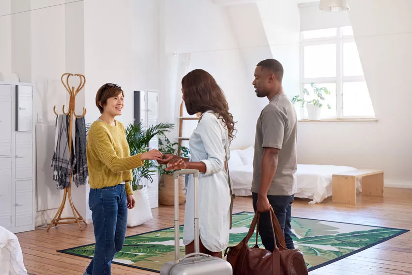 Excited host greets guests into stylish apartment